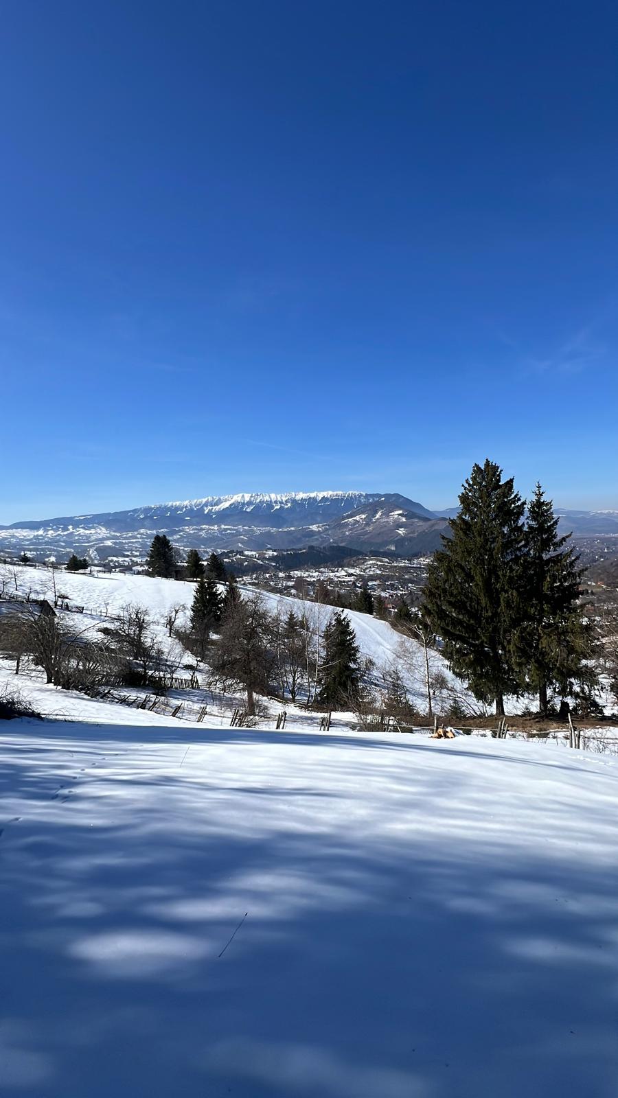 Peisaj de iarnă cu zăpadă și vedere spre creasta montană