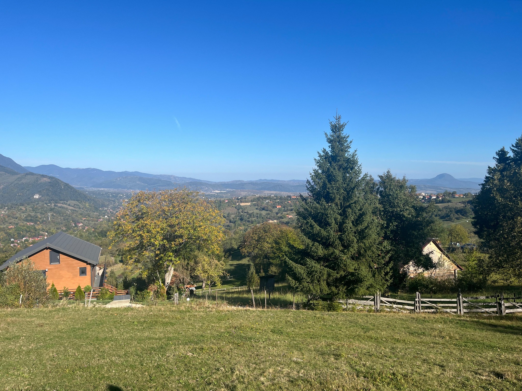 Priveliște panoramică peste teren, case și dealurile din jur